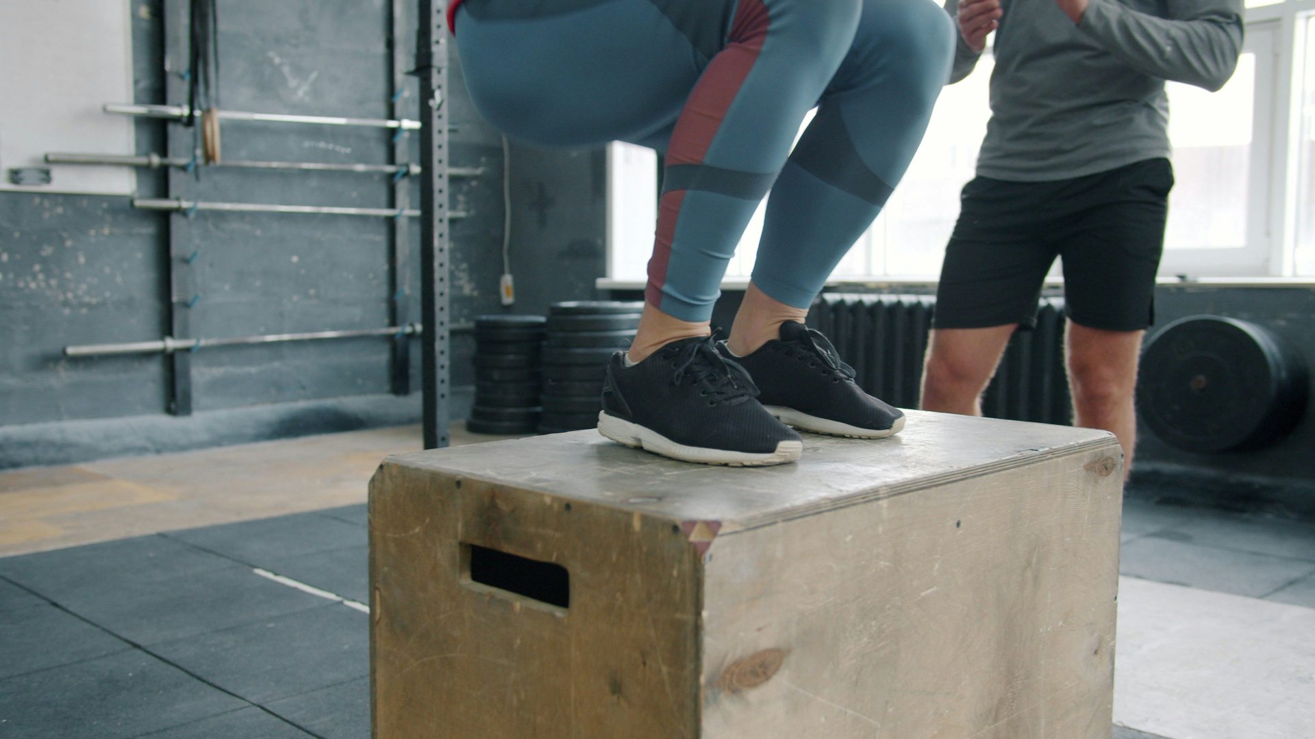 Woman jumping onto a wooden box in a gym